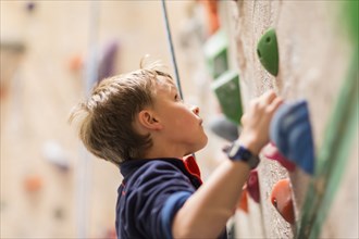 Caucasian boy climbing rock wall indoors