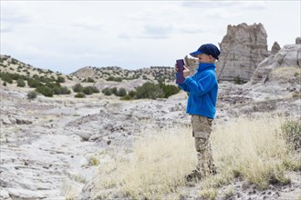 Boy photographing rock formations in desert landscape
