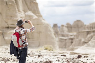 Caucasian hiker photographing desert rock formations