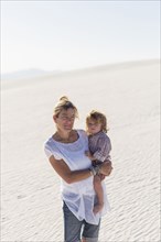 Caucasian mother holding son on desert sand dune