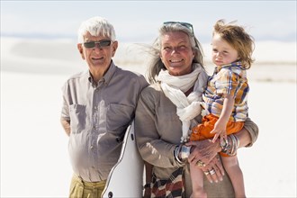 Caucasian grandparents and grandson smiling in desert