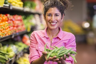 Hispanic woman holding vegetables at grocery store