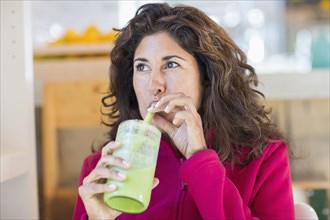 Hispanic woman drinking green juice