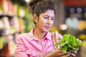 Hispanic woman examining produce at grocery store