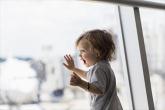 Caucasian baby boy looking out airport window