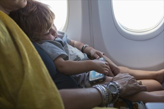 Caucasian mother holding baby son on airplane