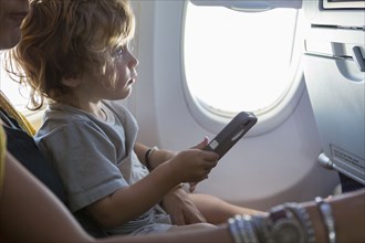 Caucasian mother and baby son using cell phone on airplane