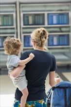 Caucasian mother carrying son in airport