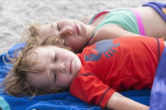 Caucasian brother and sister napping on beach