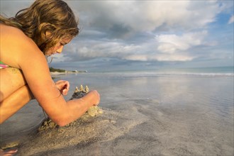 Caucasian girl building sandcastle on beach