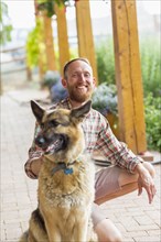 Caucasian man petting dog on patio