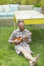 Caucasian man playing ukulele in backyard