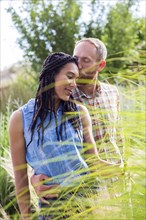 Couple kissing in tall grass in garden