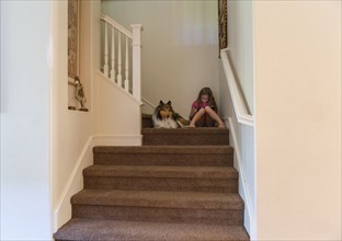 Caucasian girl and dog sitting on stairs