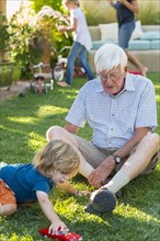Caucasian grandfather and grandson playing on lawn