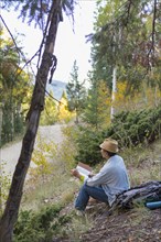 Man reading book on rural hillside