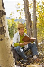 Man reading book in autumn forest