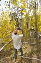 Man photographing with digital tablet in autumn forest