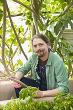 Caucasian gardener using digital tablet in greenhouse
