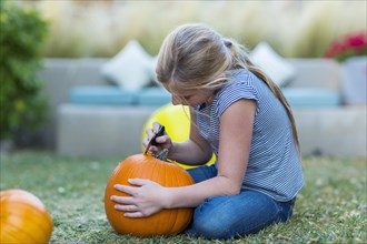 Caucasian girl carving pumpkin