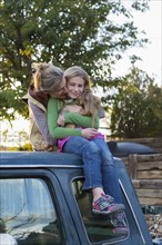 Caucasian mother hugging daughter on roof of truck