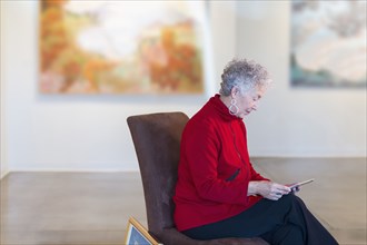 Older mixed race woman using digital tablet in art gallery
