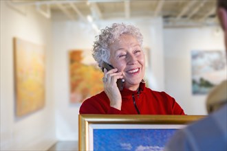 Older mixed race woman using cell phone in art gallery