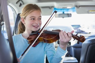 Caucasian girl playing violin in car