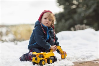 Caucasian boy playing with truck in snow