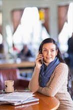 Hispanic woman talking on cell phone in cafe