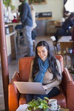 Hispanic woman using laptop in cafe