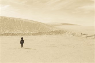 Caucasian preschooler boy walking in desert