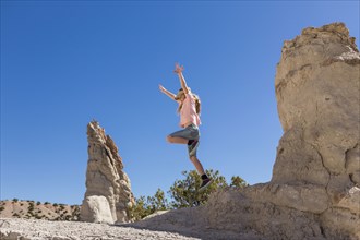 Caucasian girl jumping off rock formation
