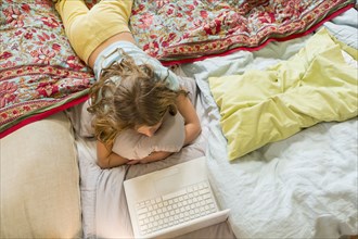 Caucasian girl using laptop on bed
