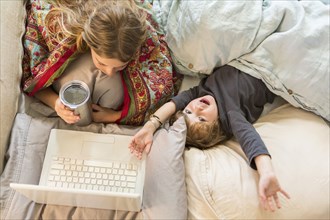 Caucasian children relaxing in bed with laptop