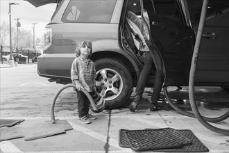 Caucasian preschooler boy helping clean car