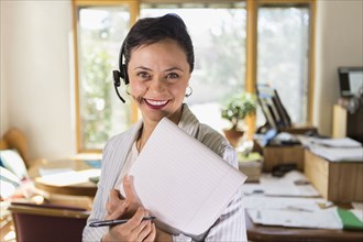 Businesswoman using notepad and headset in office