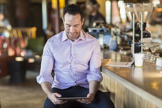Hispanic businessman using digital tablet in coffee shop