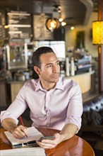 Hispanic businessman using cell phone in coffee shop