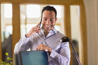 Hispanic businessman talking on cell phone in office