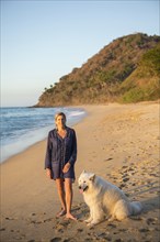 Caucasian woman posing on beach with dog