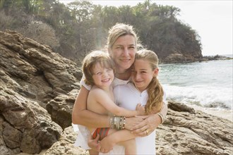 Caucasian mother hugging son and daughter at beach