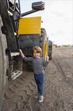 Caucasian boy holding ladder on tractor