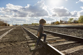 Caucasian boy crossing railroad tracks