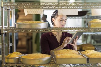Caucasian woman using digital tablet in bakery