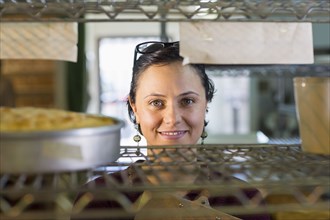 Caucasian woman smiling at shelf in bakery