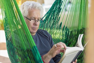 Caucasian man reading book in green hammock