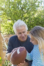 Caucasian grandfather showing granddaughter how to hold football