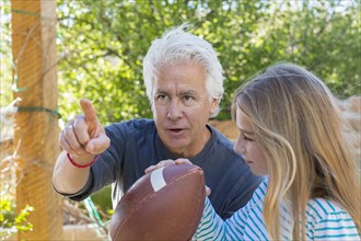 Caucasian grandfather showing granddaughter how to aim football