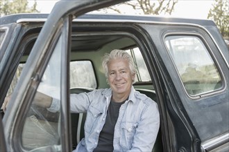 Caucasian man sitting in truck with door open